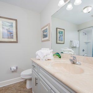 Refresh in the guest bathroom featuring a spacious tub/shower, elegant fixtures, and beach art for a soothing stay
