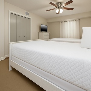 Guest bedroom featuring two queen beds, a ceiling fan, a TV, and serene atmosphere