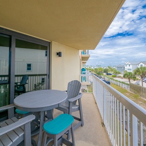 Enjoy a relaxing moment on the balcony with a table and chairs, overlooking charming coastal homes and palm trees