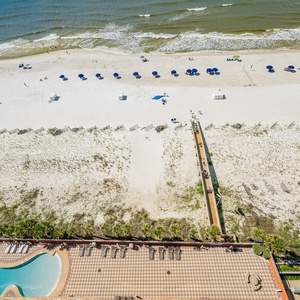 Inviting gradual entry pool area with a waterslide and lounge chairs, leading to the beach for a relaxing day