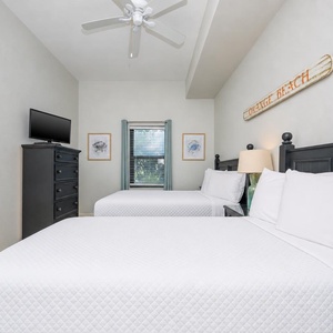 Inviting guest bedroom featuring two beds, a TV, and beach decor for a relaxing getaway