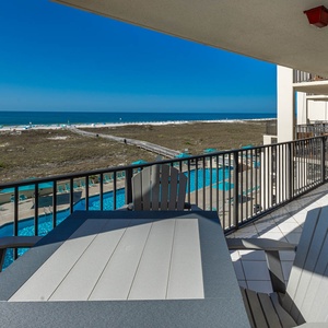 Expansive balcony view with a dining table of the beach and pool area, perfect for relaxing under the sun