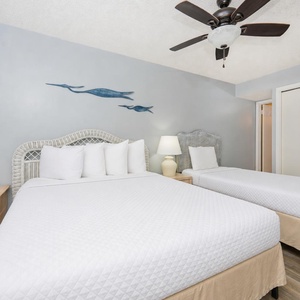Guest bedroom featuring a queen bed with white linens, a twin bed, and coastal decor, creating a relaxing atmosphere
