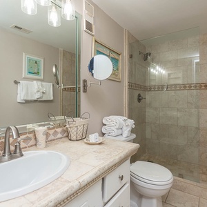 This bathroom features elegant tile work, a spacious shower, and a well-lit vanity for a refreshing guest experience