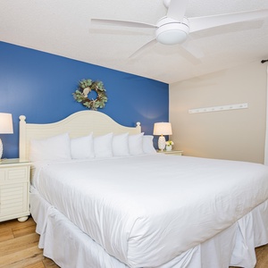 The inviting bedroom features a plush king bed, blue accent wall, and soft lighting from bedside lamps