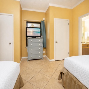 Two double beds and a dresser with a TV, creating a cheerful atmosphere in this cozy guest room
