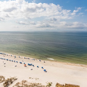 Savor gulf breezes while watching colorful umbrellas and gentle waves along the beach below