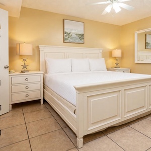 Unwind in the serene king suite featuring a comfortable bed, soft lighting, and charming coastal decor