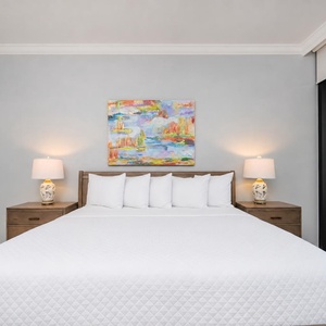 Unwind in this serene master bedroom featuring a king bed, soft lighting, and fluffy pillows