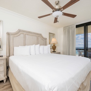 Bright and airy master bedroom featuring a king bed, elegant furnishings, and access to a balcony with views of the gulf