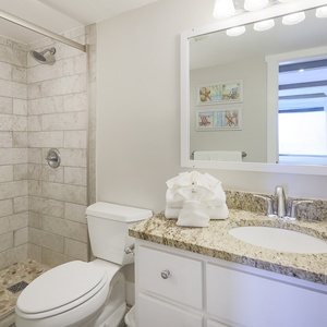 This bathroom features elegant granite countertops, a spacious shower, and a bright, welcoming atmosphere