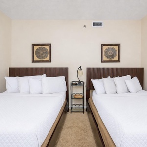 Spacious guest bedroom featuring two queen beds, decorative pillows, and soft lighting for a restful stay