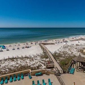 Relax on the sandy shore with vibrant beach chairs and a scenic view of the sparkling water and lively beachgoers