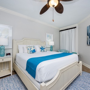 Drift off in the serene master bedroom featuring a plush king bed, coastal decor, and soft lighting for a restful retreat