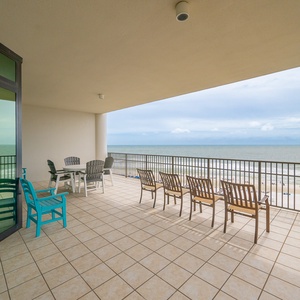 Spacious corner balcony with comfortable seating and a breathtaking view of the beach and rolling waves