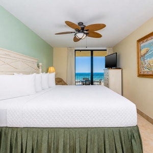 Master bedroom with a plush king bed and a balcony offering breathtaking views of the sparkling waters