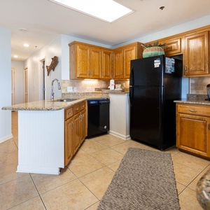 The kitchen features wooden cabinets, a black refrigerator, Keurig coffee station, and a breakfast bar area