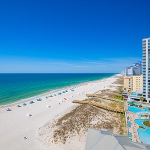 This stunning beachfront view showcases soft white sand and gentle waves, perfect for relaxation and enjoyment