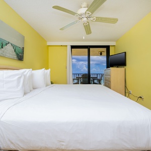 Master suite featuring a plush king bed, a TV, and the balcony with a view of the beach front
