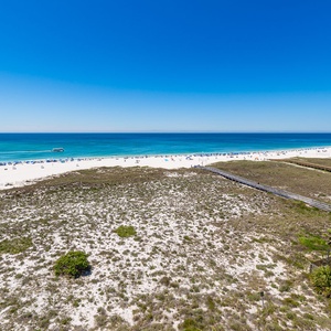Bright blue skies stretch above the coastline where you watch boats and beachgoers enjoy the day