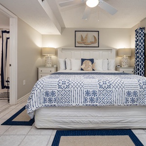 The master bedroom features a king bed with nautical decor, soft lighting, and the adjoining modern bathroom