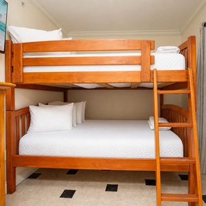 Rest comfortably in this charming bunk room featuring a wooden twin bunk and cozy linens for a restful night's sleep