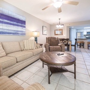 Living area features a cozy sofa with queen sleeper, a rustic coffee table, and a view into the dining area and kitchen