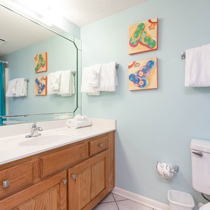 Refresh in the guest bathroom, featuring a spacious vanity, colorful artwork, and neatly arranged towels