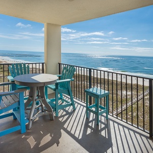 Balcony with turquoise patio set offers a serene view of the sun glistening off the beach sand and gulf waters