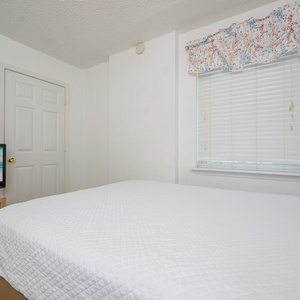 This cozy bedroom features a comfortable bed with stylish bedding and a TV for entertainment, perfect for a relaxing stay
