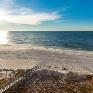Glistening waves reflect the sun above a serene beach front, inviting relaxation on the soft white sand below