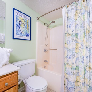 Fresh towels stack high beside the tub where you'll enjoy rinsing off in this guest bath after a beach day
