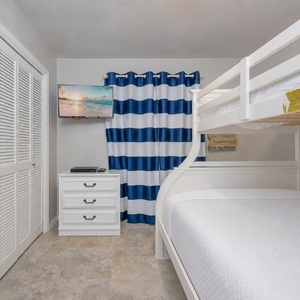 Bunk room invites kids to unwind under striped curtains while streaming shows on the wall-mounted TV