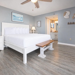 The master bedroom features a comfortable king bed, charming coastal decor, and a cozy seating area, perfect for relaxation