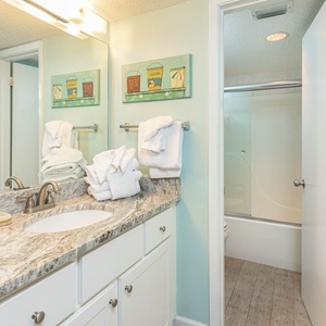 Experience a refreshing master bath with a spacious countertop, soft towels, and cheerful coastal decor