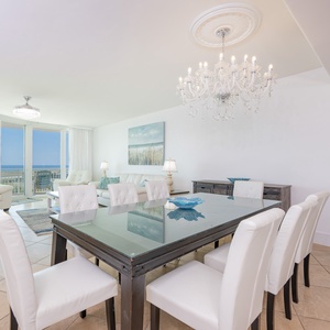 Bright and airy living space featuring a chic dining table, plush white sofas, and breathtaking coastal views