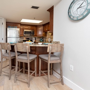 Warm wood cabinetry complements the modern breakfast bar with seating, creating a welcoming space