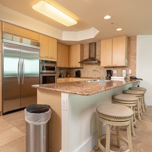 This kitchen features sleek and modern appliances, granite countertops, and a cozy breakfast bar for casual dining