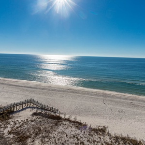 Breathtaking view of the sparkling coastline and serene beach under a clear blue sky from a serene balcony