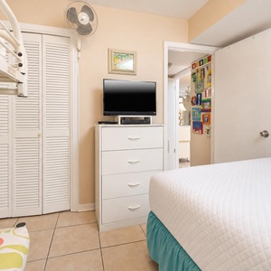 This guest bedroom features a comfortable bed, a TV for entertainment, and colorful wall art that adds charm