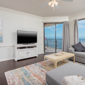The inviting living room features a gray sofa, a wooden coffee table, and large windows showcasing a beautiful beach view