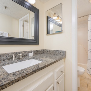 The master bathroom features a granite countertop, a large mirror, and a tub/shower combo behind a patterned curtain