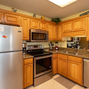 The kitchen features warm wood cabinetry, granite countertops, and a convenient breakfast bar for entertaining