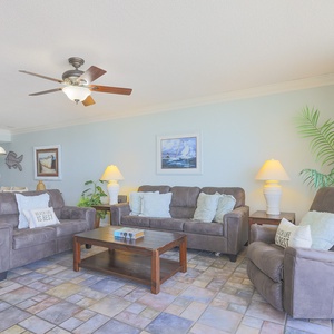 Spacious living area features two plush sofas, a queen sleeper, coffee table, and tropical decor, creating a relaxing vibe