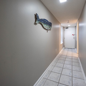 Welcoming hallway featuring tiled flooring and a decorative wooden whale accent, leading to the entrance door