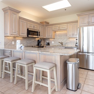 Light wood cabinetry and granite countertops enhance this modern kitchen with a breakfast bar and four stylish stools