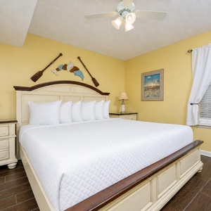 Bright yellow walls complement the coastal decor in this inviting bedroom featuring a king bed and nightstand