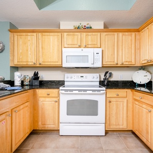 Kitchen featuring light wood cabinetry, granite countertops, and modern appliances for a delightful cooking experience