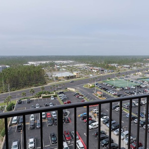 This balcony view showcases a vibrant landscape with lush greenery and nearby amenities, perfect for your getaway