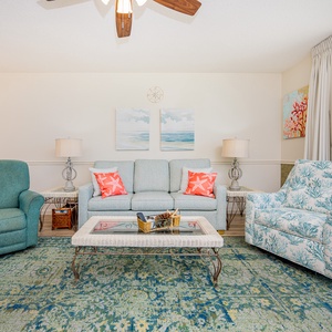 Relax in the comfortable living area adorned with beach-themed decor and a vibrant area rug, perfect for unwinding